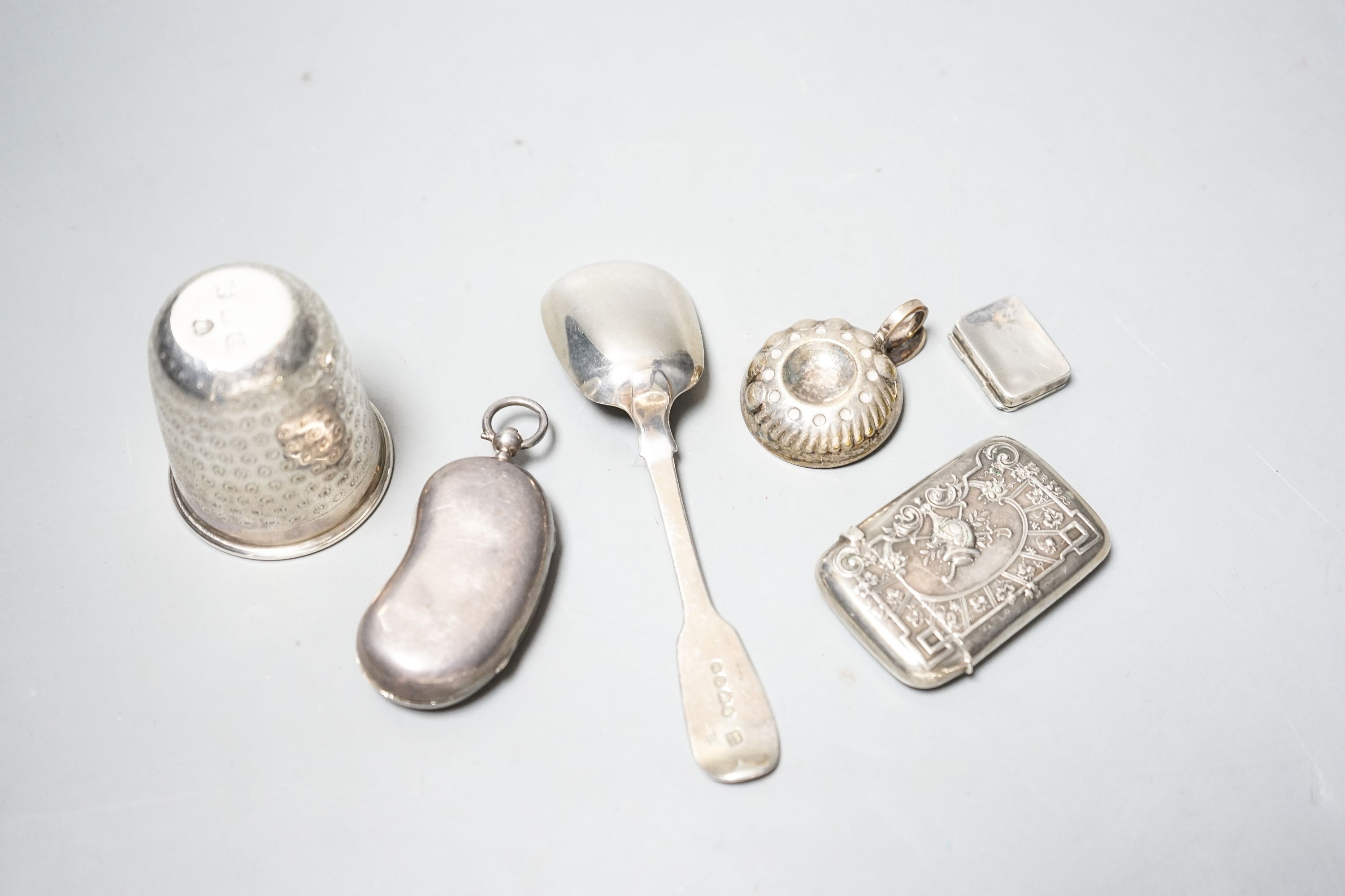 A George V silver twin sovereign kidney shaped case, 65mm, a silver spoon, silver tot , silver pill box, a German 800 vesta case and a plated small taste vin.